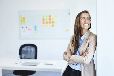 Portrait of cheerful businesswoman smiling and looking away in office - BSZF01486