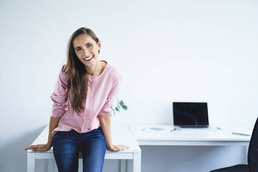 Young woman smiling at camera in office - BSZF01507