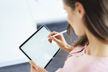 Over the shoulder view of woman drawing on tablet using pencil - BSZF01512