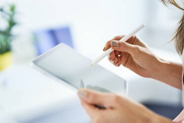 Close up of woman using pen and tablet in office - BSZF01513