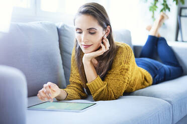 Young oman lying on sofa and using tablet - BSZF01541