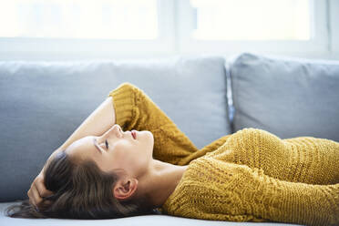 Young woman lying on sofa with eyes closed and relaxing - BSZF01542