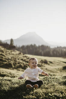 Glücklicher kleiner Junge auf einer Alpwiese sitzend, Schwaegalp, Nesslau, Schweiz - LHPF01093