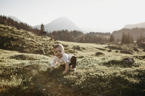 Fröhlicher kleiner Junge krabbelt auf einer Alpwiese, Schwaegalp, Nesslau, Schweiz - LHPF01094
