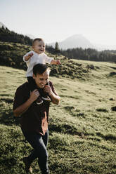 Glücklicher Vater trägt seinen kleinen Sohn auf den Schultern auf einer Wanderung, Schwaegalp, Nesslau, Schweiz - LHPF01100