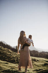 Rückansicht einer Mutter, die ihren kleinen Sohn auf einer Wanderung hält, Schwaegalp, Nesslau, Schweiz - LHPF01103