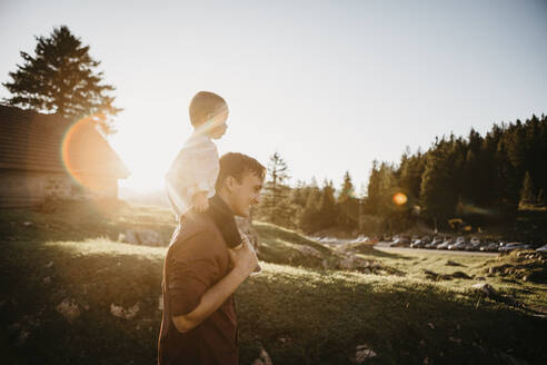 Father carrying little son on shoulders on a hiking trip at sunset, Schwaegalp, Nesslau, Switzerland - LHPF01106