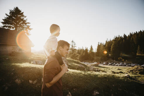 Vater trägt kleinen Sohn auf den Schultern auf einer Wanderung bei Sonnenuntergang, Schwaegalp, Nesslau, Schweiz - LHPF01106