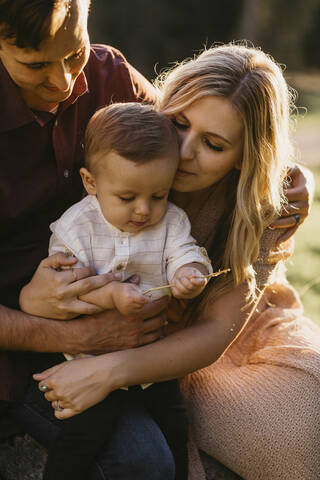 Liebevolle Familie mit kleinem Sohn im Freien bei Sonnenuntergang, lizenzfreies Stockfoto