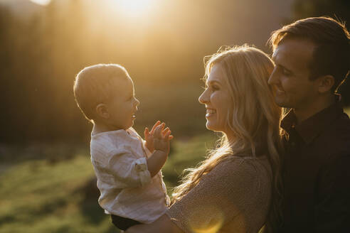 Glückliche Familie mit kleinem Sohn im Freien bei Sonnenuntergang - LHPF01117