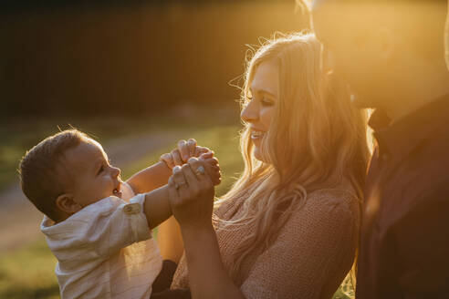 Glückliche Familie mit kleinem Sohn im Freien bei Sonnenuntergang - LHPF01118