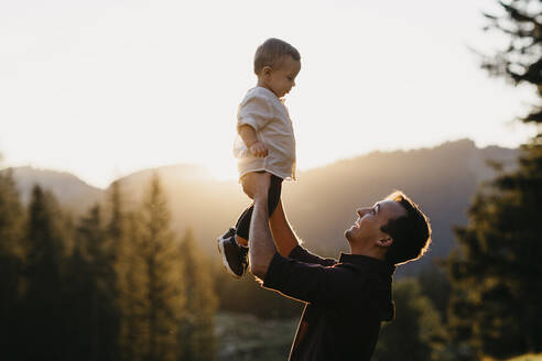 Happy father lifting up little son outdoors at sunset, Schwaegalp, Nesslau, Switzerland - LHPF01122