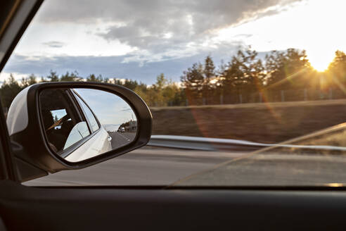 Voronezh, Voronezh Oblast, Russia, Shiny side-view mirror with sun setting in background - VGF00314