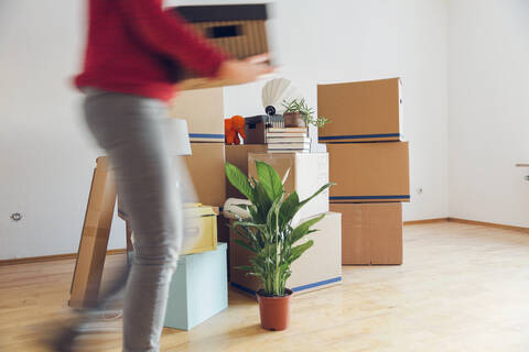 Frau trägt Karton in ein neues Haus, lizenzfreies Stockfoto