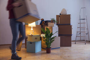 Woman carrying cardboard box in a new home - MAMF00799