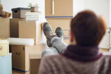 Frau entspannt sich umgeben von Kartons in einer neuen Wohnung - MAMF00841