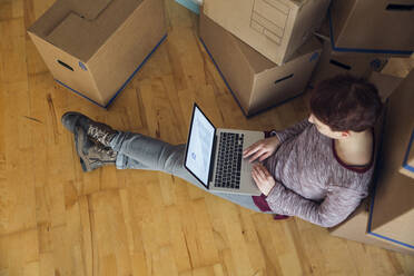 Woman using laptop with rising line graph on the screen in a new home - MAMF00856