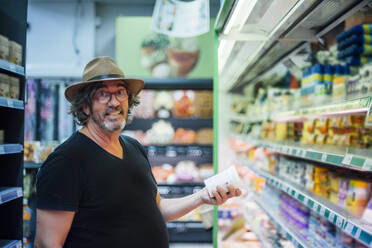 Porträt eines älteren Mannes, der in einem Supermarkt Lebensmittel kauft - CJMF00116