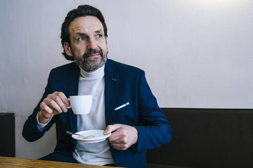 Porträt eines reifen Geschäftsmannes mit einer Tasse Kaffee in einem Cafe - JLOF00324