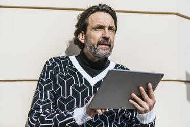Porträt eines modischen reifen Mannes mit digitalem Tablet - JLOF00343