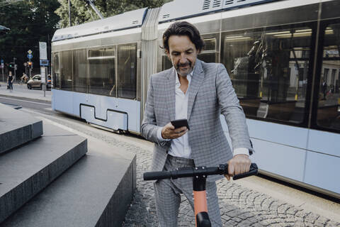 Geschäftsmann, der einen E-Scooter in der Stadt mietet, lizenzfreies Stockfoto