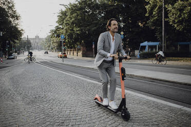 Geschäftsmann mit E-Scooter in der Stadt - JLOF00364