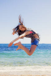Mädchen, das an der Strandpromenade in die Luft springt - XCF00282