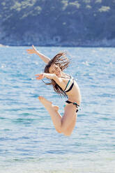 Portrait of girl jumping in the air in front of the sea - XCF00285