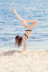 Girl practicing handstand on the beach - XCF00286