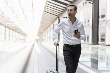 Businessman on moving walkway at the airport - DIGF08459