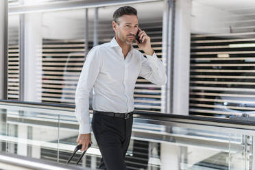 Businessman on escalator talking on the phone - DIGF08460