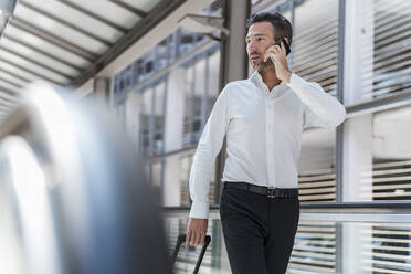 Businessman on escalator talking on the phone - DIGF08461