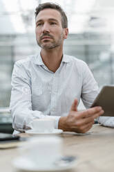 Portrait of businessman with tablet in a cafe - DIGF08468