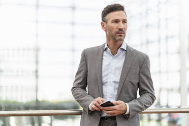 Portrait of businessman holding cell phone - DIGF08481