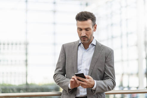 Porträt eines Geschäftsmannes, der ein Mobiltelefon benutzt - DIGF08482