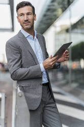 Portrait of confident businessman holding tablet - DIGF08486