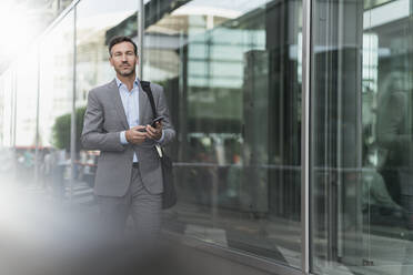 Portrait of businessman with cell phone on the go - DIGF08490