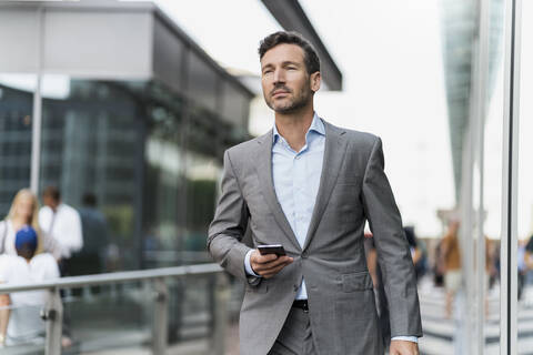 Porträt eines Geschäftsmannes mit Mobiltelefon, der unterwegs ist, lizenzfreies Stockfoto