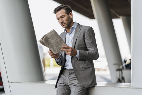 Porträt eines Geschäftsmannes, der im Freien Zeitung liest, lizenzfreies Stockfoto