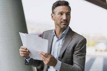 Portrait of businessman holding papers outdoors - DIGF08500