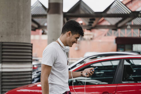 Young man waiting at train station using smartphone - JMHMF00017