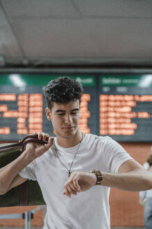 Young man checking the time at train station - JMHMF00019