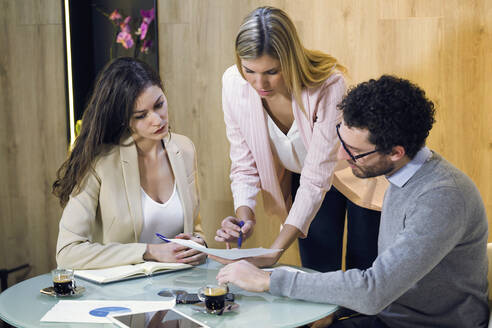 Drei Geschäftsleute, die sich in einem modernen Büro treffen und ein Dokument besprechen - JSRF00681