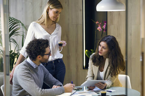 Drei Geschäftsleute bei einem Treffen in einem modernen Büro, lizenzfreies Stockfoto