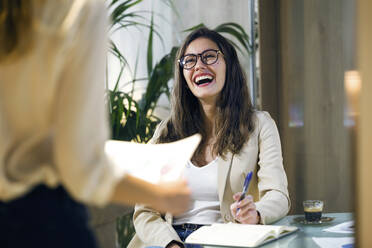 Laughing businesswoman looking at colleague in modern office - JSRF00686