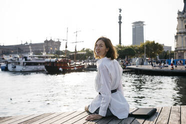 Pretty businesswoman sitting at the marina after work, relaxing - JRFF03777