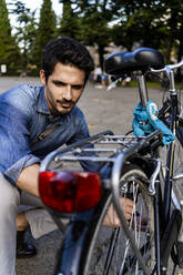 Mann in der Stadt bei der Kontrolle seines Fahrrads - GIOF07176