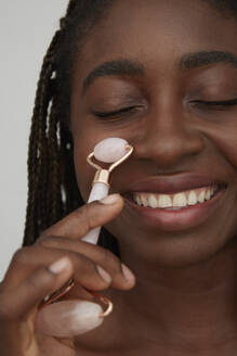 Portrait of African woman using jade roller - PGCF00033