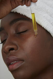 Porträt einer afrikanischen Frau mit Pipette, Hautpflege - PGCF00034