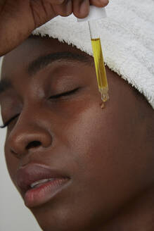 Portrait of African woman using pipette, skin care - PGCF00034